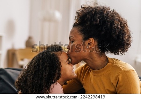 Loving mother is kissing her daughter in the forehead