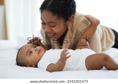 African young mother playing with her adorable baby on bed