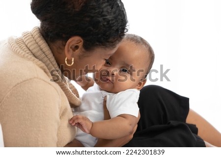 African young mother carrying and kissing with her adorable baby on bed