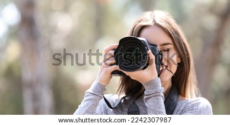 Beautiful female photographer with modern camera outdoors