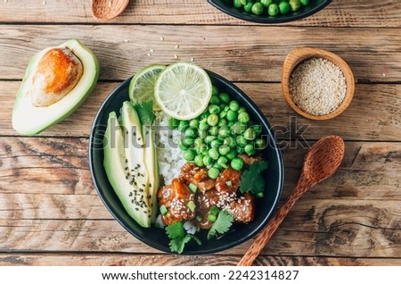Buddha bowl with crispy sesame chicken asian style. Sweet and sour fried chicken with steamed rice, peas and acocado Royalty-Free Stock Photo #2242314827