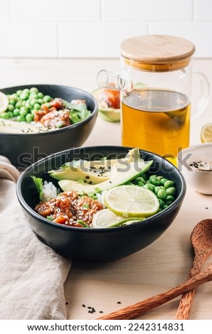 Buddha bowl with crispy sesame chicken asian style. Sweet and sour fried chicken with steamed rice, peas and acocado Royalty-Free Stock Photo #2242314831