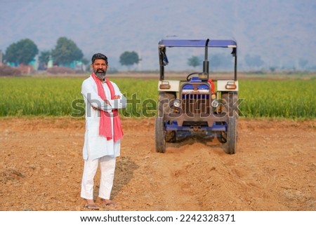 indian farmer standing near tractor at agriculture field. Royalty-Free Stock Photo #2242328371
