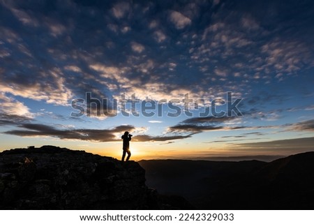 woman taking pictures at sunset in orange sky
