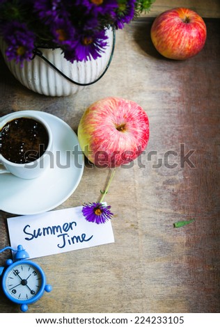 Cup of coffee, apples and aster flowers in a vase on the wooden table