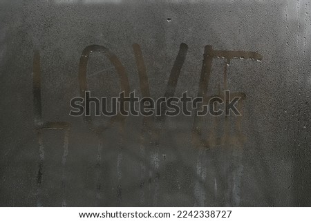 the word love on wet glass. Condensation on window