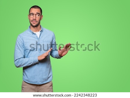 Doubtful young man doing a gesture of keep calm