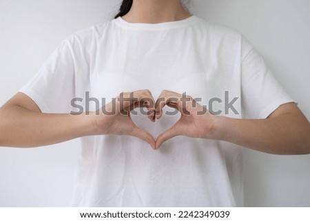 Asian young women making hand sign hearts. Beautiful hand and finger gesture shape symbol of love. Concept Valentine's day. The model wears a white t-shirt. Isolated on white background, copy space.