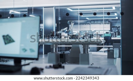 Modern High Tech Robotic Arm Picking Up and Moving a Microchip. Robot Hand Working at a Research and Development Factory with Server Racks in the Background. Royalty-Free Stock Photo #2242349343