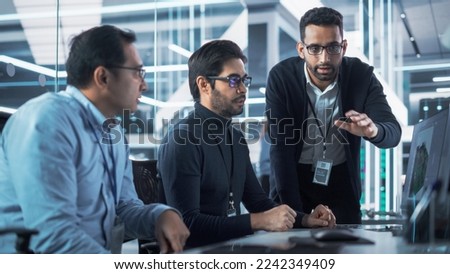 Team of Three Handsome Talented Young Engineers Use Computer to Discuss a Technological Project in Industry 4.0 Modern Factory Office. Group of Scientists Work in Research and Development Center. Royalty-Free Stock Photo #2242349409