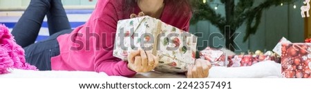 Girl with a gift in a box near the Christmas tree