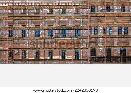Blank white long banner with place for mockup fixed on building facade wall with scaffold during reconstruction outside