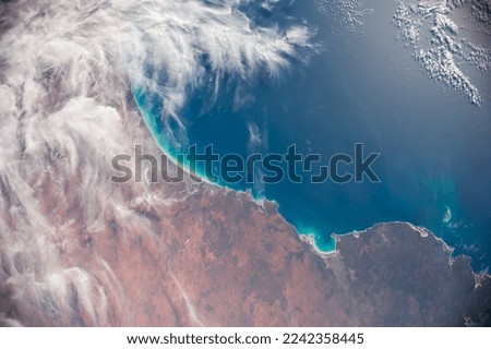Photograph of the coastline from space. Cloud clusters and small islands above the ocean. Stunning beach aerial view. Elements of this image furnished by NASA.