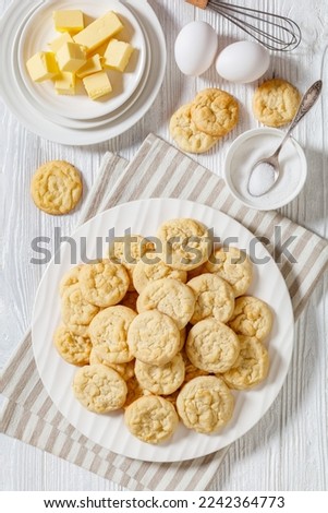 amish sugar cookies, traditional shortbread sweet cookies on white plate on white wood table with ingredients, american cuisine, vertical view from above, flat lay