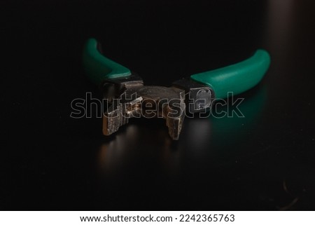 Pliers Open metal nippers with a red and green handle isolated on black background