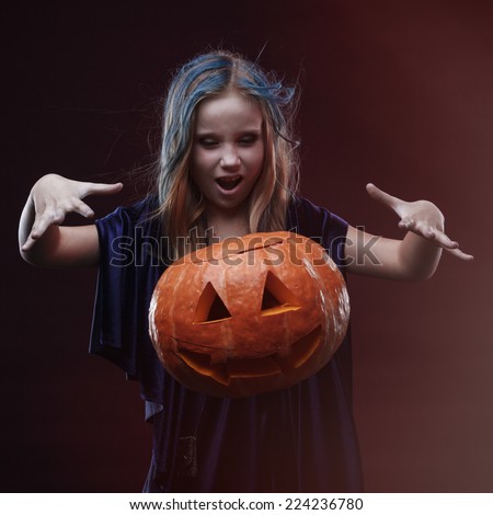Little girl in halloween costume of the witch with the pumpkin make spell conjure
