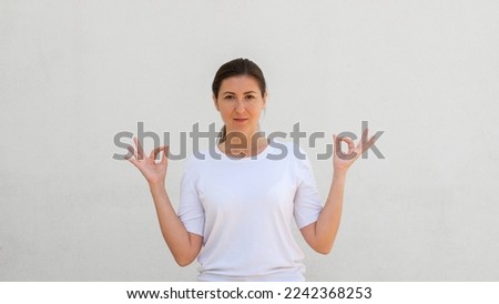 Portrait of calm young woman doing relaxation exercise over white background. Caucasian woman wearing white T-shirt meditating. Harmony and balance concept