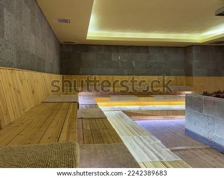 Seat in sauna room. Empty wooden steam room with stone heater.Sauna room for good health. Sauna room with traditional sauna accessories.Healthy and spa life style.