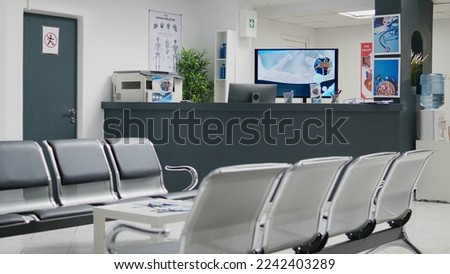 Empty hospital waiting room in lobby with reception counter at medical facility, used to help patients with appointments and healthcare insurance. Medical waiting area with front desk. Royalty-Free Stock Photo #2242403289