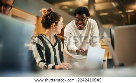 Portrait of Two Creative Young Colleagues Consulting Eachother Using Laptop in Modern Office. Black Male Supervisor Discussing Scheduling with Female Hispanic Head of Operations.. Royalty-Free Stock Photo #2242410045
