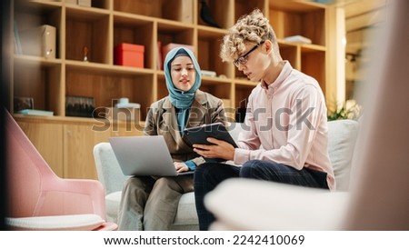 Two Creative Colleagues Collaborating Over a Work Project Using Computer and Tablet at Office. Male E-commerce Marketing Manager Discussing with Muslim Female Media Planner. Medium