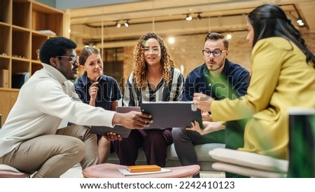 Multiethnic Group of Creative People Working on Project in a Modern Bright Office. A Diverse Group of Colleagues Developing a New Approach Using Charts, Laptop, and Tablet. Wide Shot Royalty-Free Stock Photo #2242410123