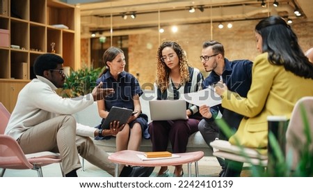 Group of People from Multiple Ethnicities Working on Problem Solving Using Notes, Laptop and Tablet in a Meeting Room at the Office. Teammates Giving Constructive Feedback on Eachother's Projects Royalty-Free Stock Photo #2242410139