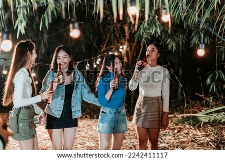 Group of female friends having fun holding bottles and drinking beer at the party