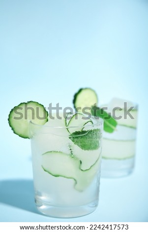 Tasty fresh cucumber water with mint on light blue background