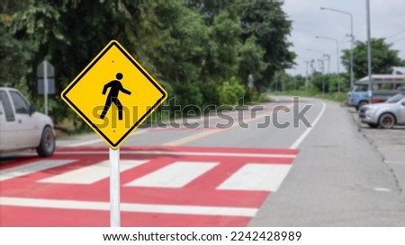 Yellow warn sign with graphic of pedestrian on blur background                           