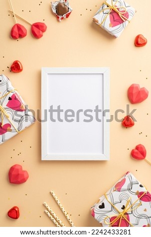 Valentine's Day concept. Top view vertical photo of photo frame gift boxes heart shaped lollipops chocolate candies straws and golden sequins on isolated pastel beige background with empty space