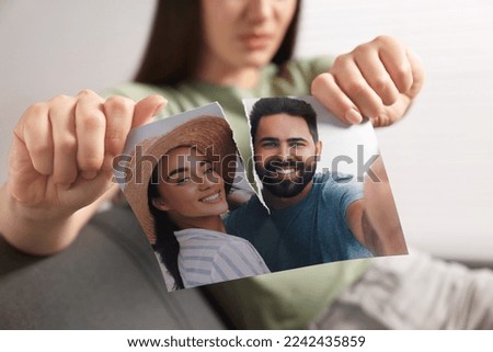 Woman ripping photo indoors, closeup. Divorce concept
