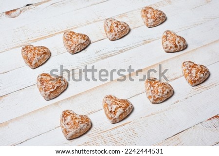 Sweet heart-shaped glazed gingerbread photographed on a white wooden surface.