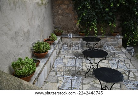 Picturesque patio with bistro furniture and clay pots with plants in Nafplio, Greece. 