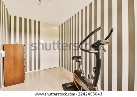 a gym room with an exercise bike on the floor and black and white striped wallpapers in the walls