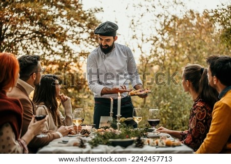 Group of diverse people enjoying summer afternoon and evening in garden party while Chef in a white unifor went out and greeting them. Royalty-Free Stock Photo #2242457713
