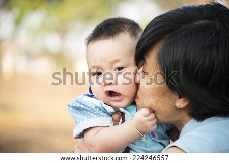 Smiling mother kissing her baby in the park