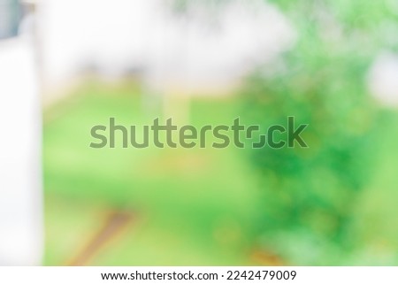 Defocused abstract background of some plants with a white building close to it. Blurred out building area background