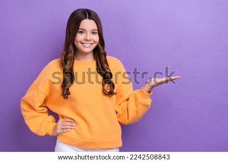 Photo of positive cute lady wear trendy orange winter clothes arm presenting nice feedback empty space isolated on purple color background