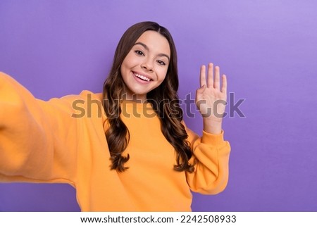 Photo of cheerful cute lady wear orange autumn clothes demonstrate greetings symbol hi online meeting isolated on purple color background