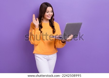 Photo of positive friendly lady wear orange sweatshirt waving arms modern gadget empty space isolated violet color background