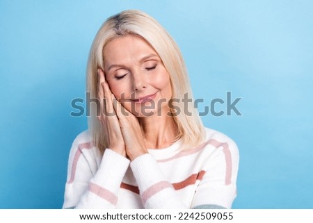 Photo of sweet dreamy woman dressed striped sweater arms cheek closed eyes isolated blue color background