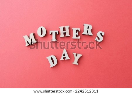 Inscription in wooden letters - mother's day. Concept greeting card. The background is red.