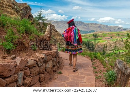 Indigenous peruvian quechua woman in traditional textile clothing walking on inca trail, Sacred valley, Cusco, Peru. Royalty-Free Stock Photo #2242512637