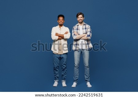 Full body young two friends happy fun cool men 20s wear white casual shirts together looking camera hold hands crossed folded isolated plain dark royal navy blue background. People lifestyle concept