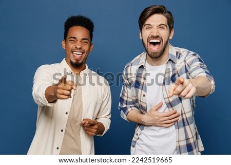 Young two friends men 20s wear white casual shirts together point finger camera on you laugh watch memes comedy mocking somebody isolated plain dark royal navy blue background People lifestyle concept Royalty-Free Stock Photo #2242519665