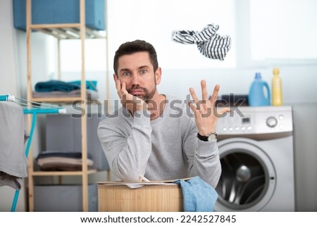 bored husband man doing laundry at home Royalty-Free Stock Photo #2242527845