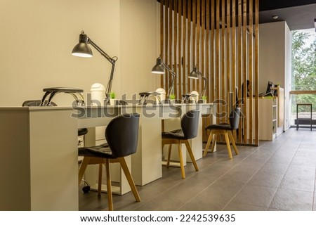 Interior of a modern beauty salon, nail area. Manicure workplace with lamps and cozy chairs in the barbershop. Concept of interior design for hairdressers and nail artists. Nail salon Royalty-Free Stock Photo #2242539635