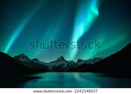 Aurora borealis. Northern lights in winter mountains. Sky with polar lights and stars. Stars reflection in lake water Royalty-Free Stock Photo #2242548037