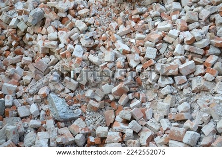 Pile of broken red bricks and fragments of concrete from destroyed building. Broken bricks close up demolition or destruction of buildings. Construction debris Royalty-Free Stock Photo #2242552075
